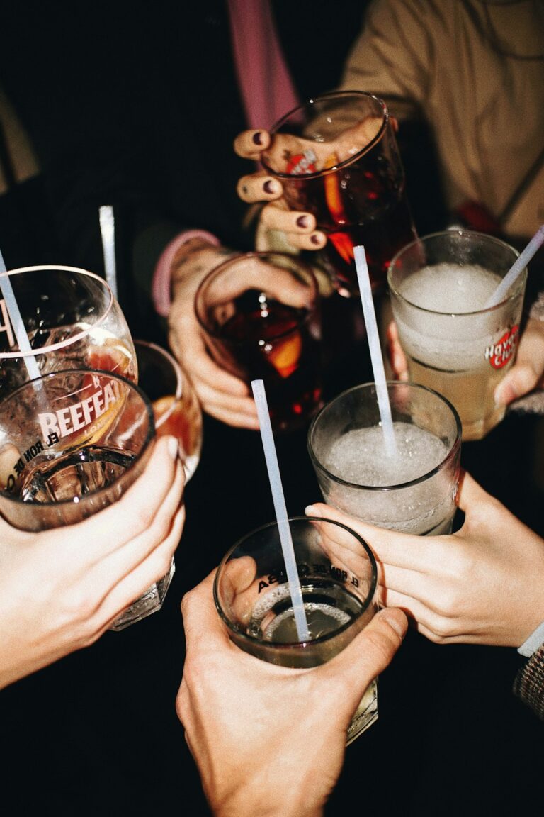 Adults share colorful alcohol-free drinks with citrus, herbs, ice, and sparkling water at a dining table.